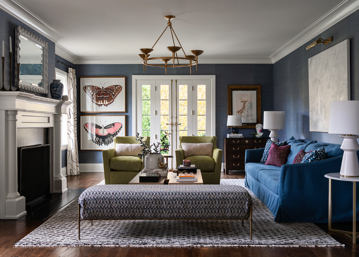 Blue living room with a blue sofa, green chairs and a patterned bench.