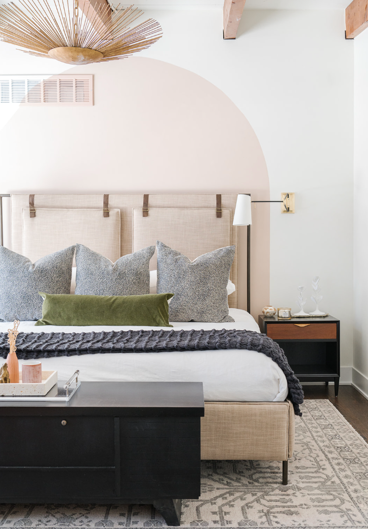 Bedroom with an upholstered bed, patterned pillows and a dark wood chest.