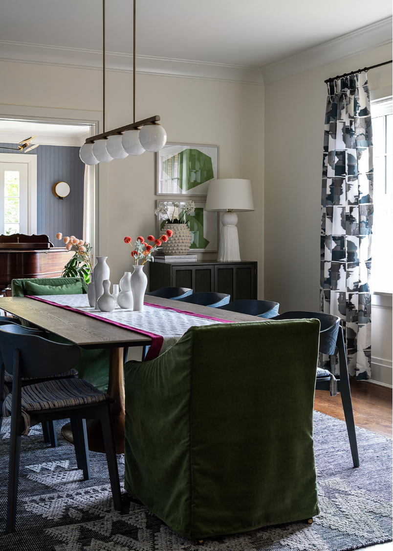 Dining room with a wood table, green end chairs and blue dining chairs.